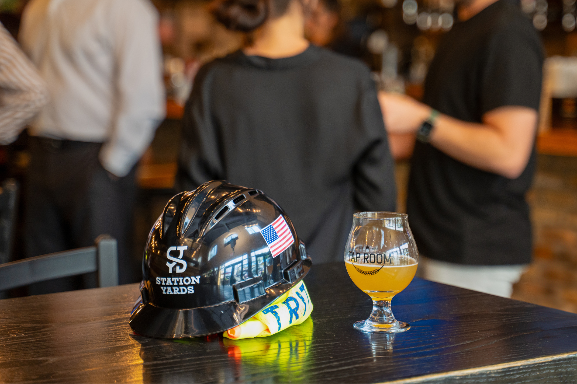 Station Yards hard hat next to a glass of beer from Tap Room