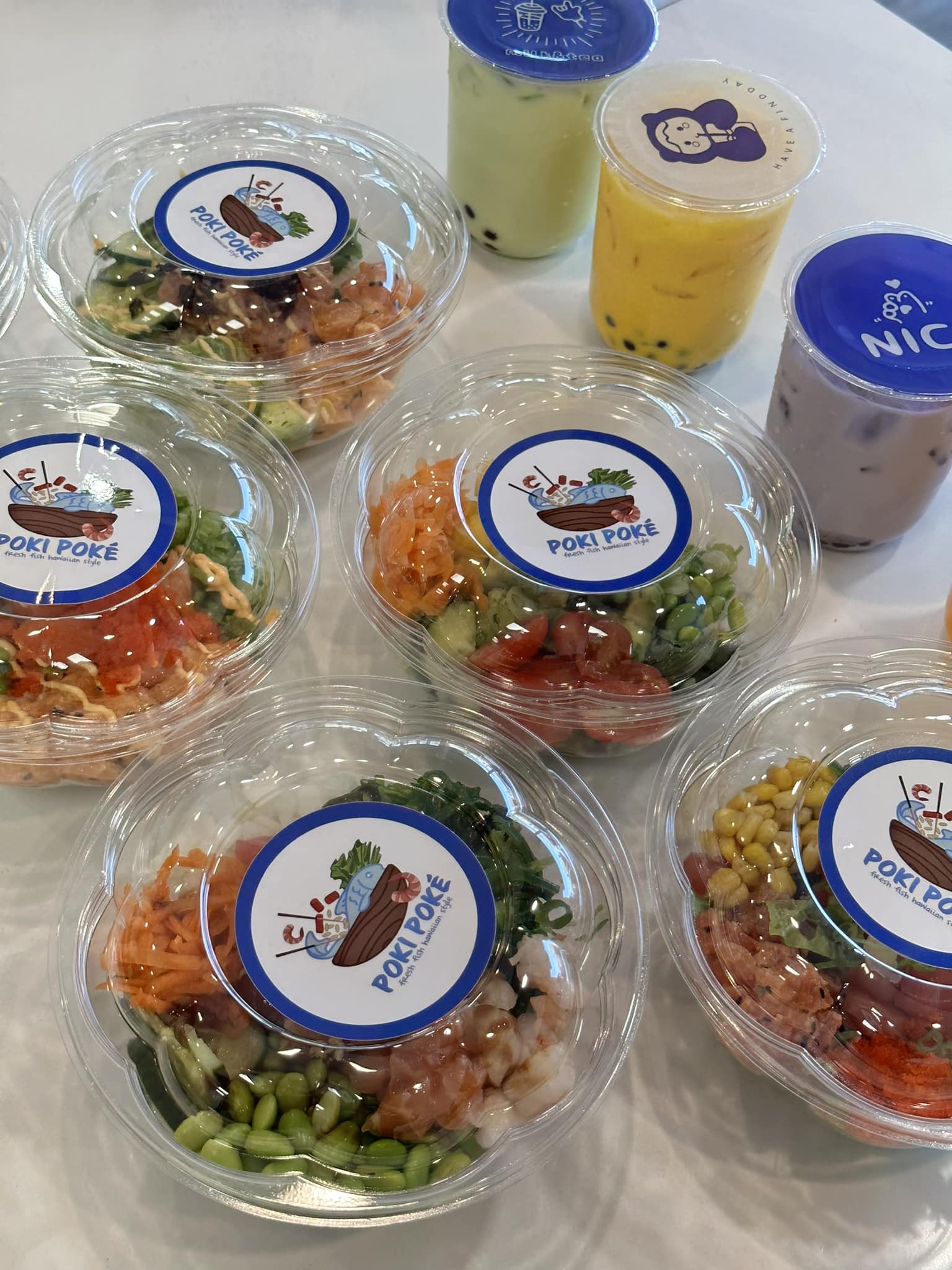 Prepackaged Poke bowls and three boba drinks with Poke Poke labeling.