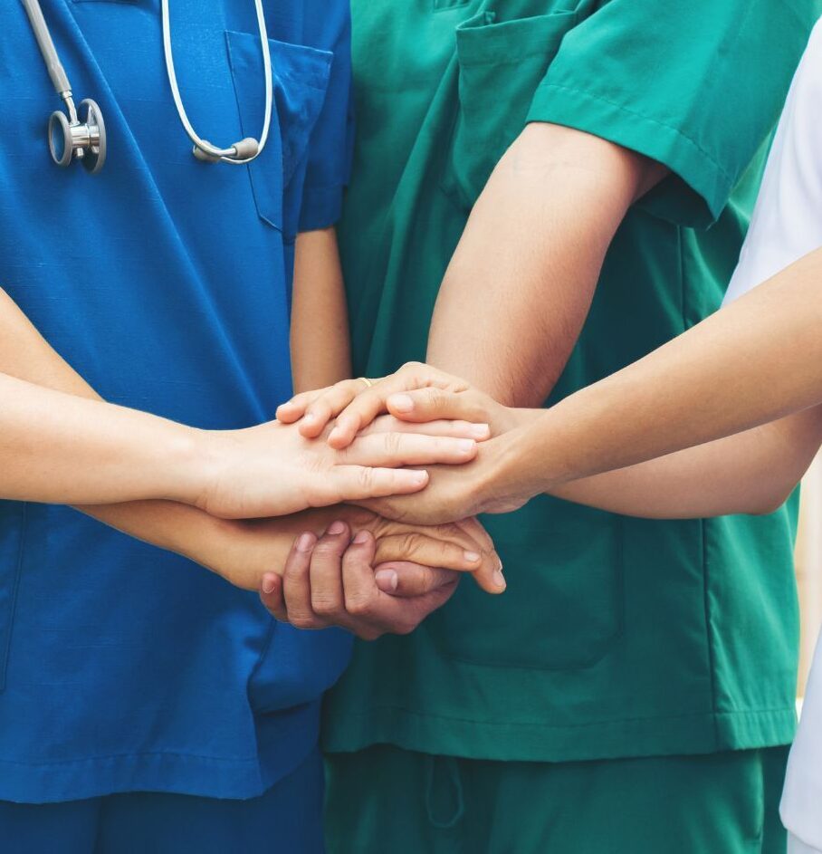 A cropped image of five healthcare workers with their hands together in the center.