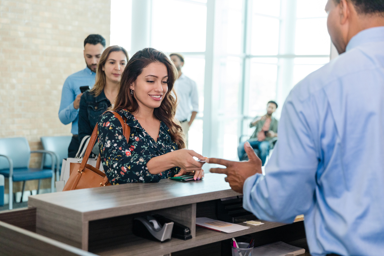 A woman at the front of a line handing over a card from her wallet to a man.