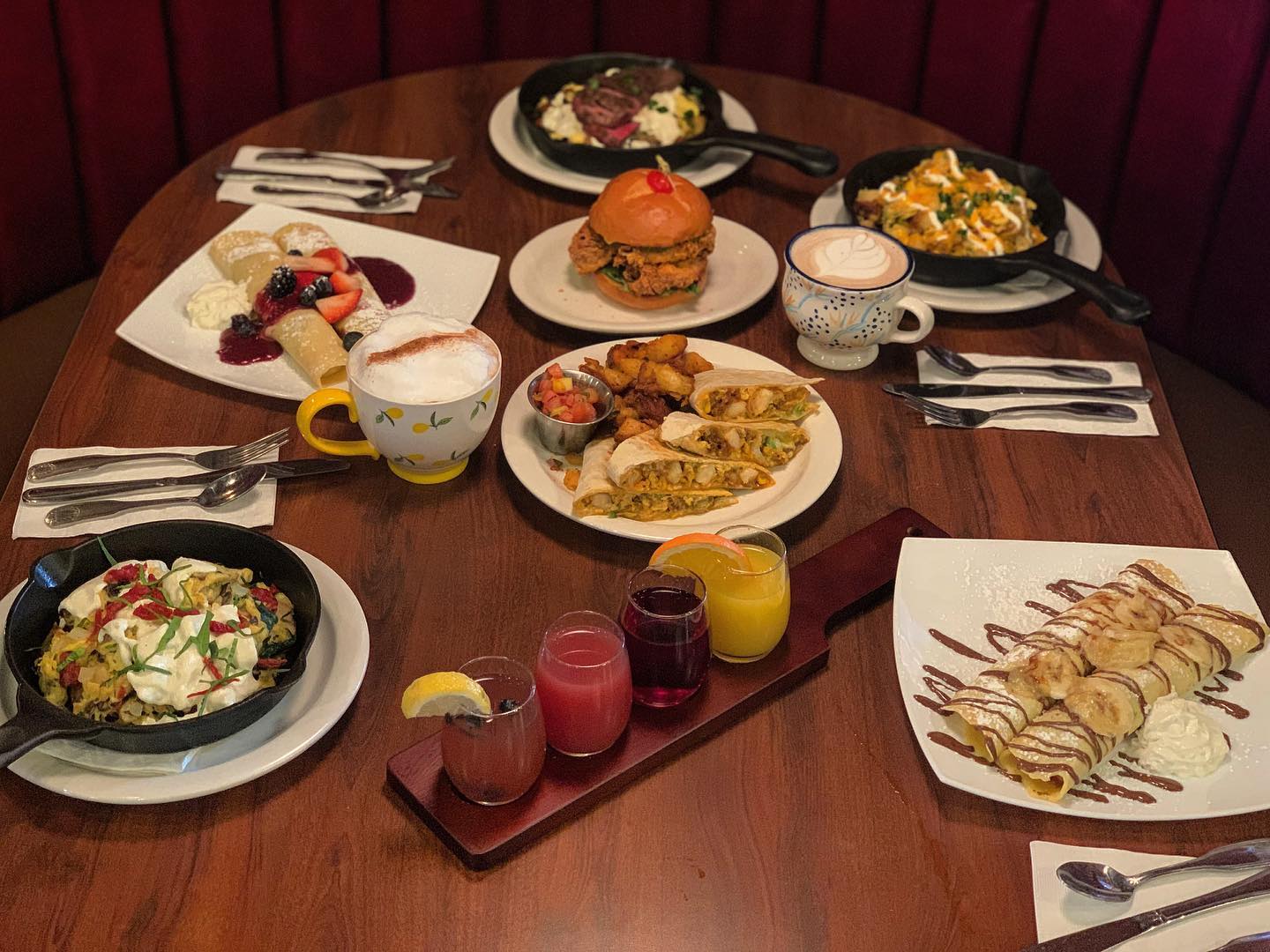 A table with 4 plates of food, two plates of desert, a rail of 4 beverages and two coffee beverages on display