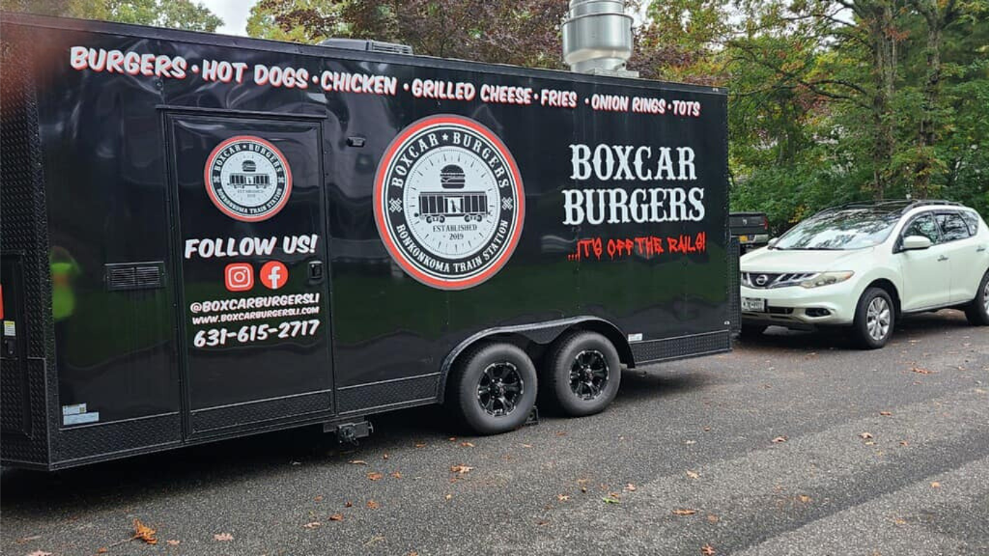 A Boxcar Burgers food truck parked in front of a white Nissan