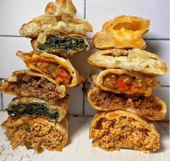 Stacked empanadas cut in half, displaying a variety of fillings.
