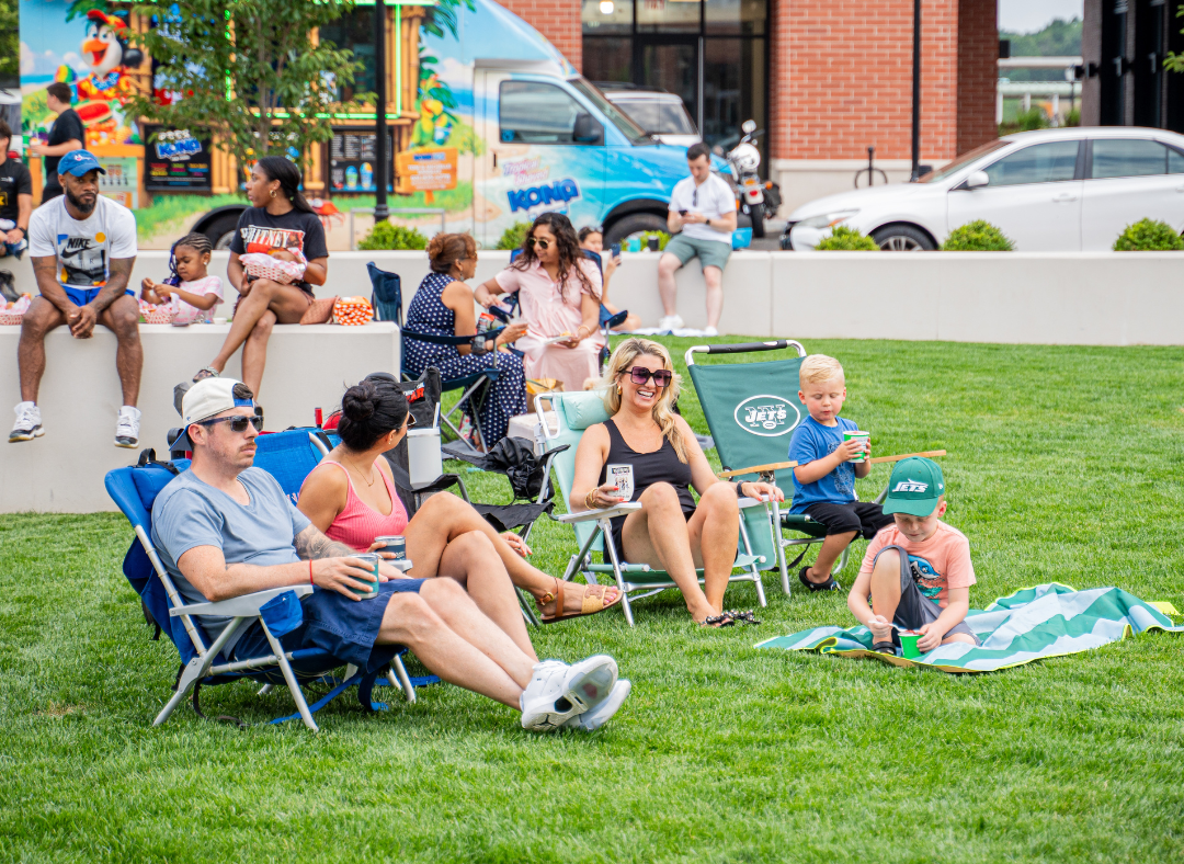 Attendees of Grooves on the Green sitting on lawn chairs and enjoying the food trucks