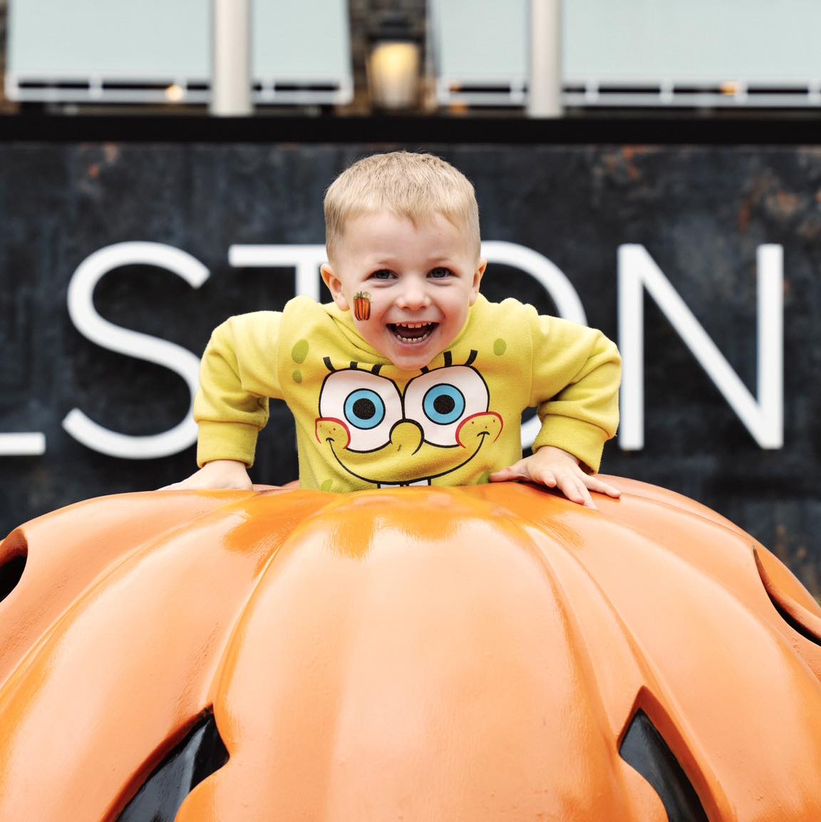 Child with pumpkin face paint at the fall festival