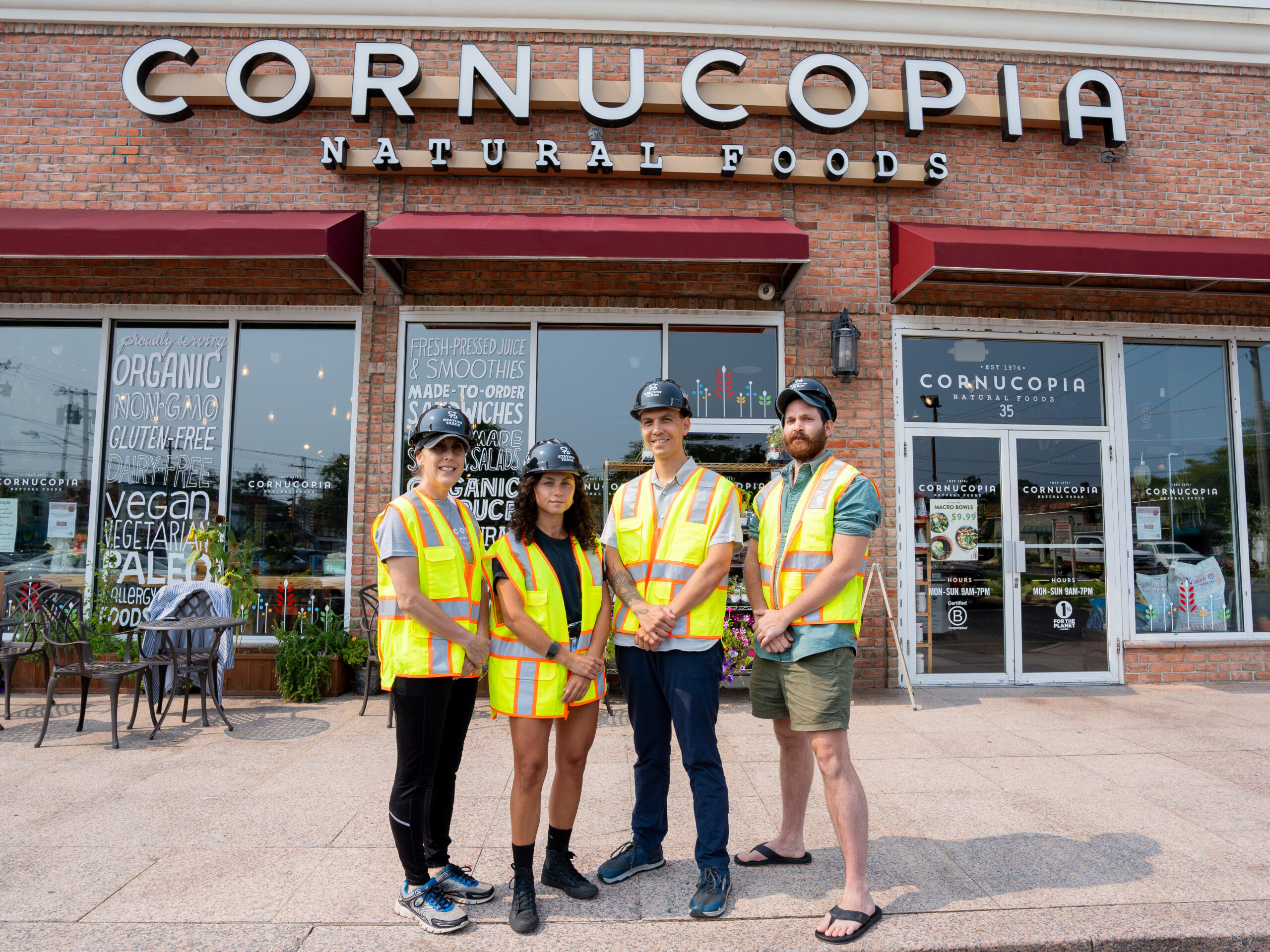 The Cornucopia Natural Foods team smiling with Station Yards hardhats and safety vests