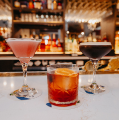 a cosmo, espresso martini, and an old fashioned on a bar top