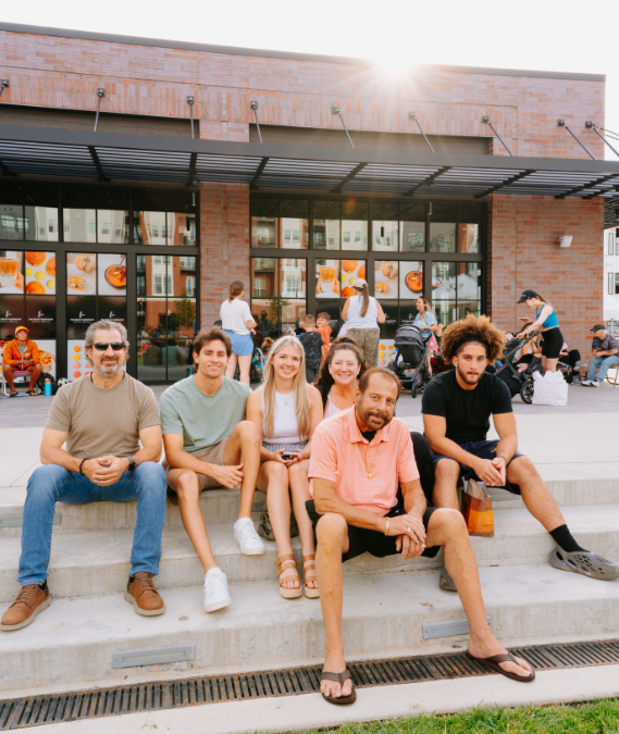 family sitting on the steps at an outdoor concert at Station Yards